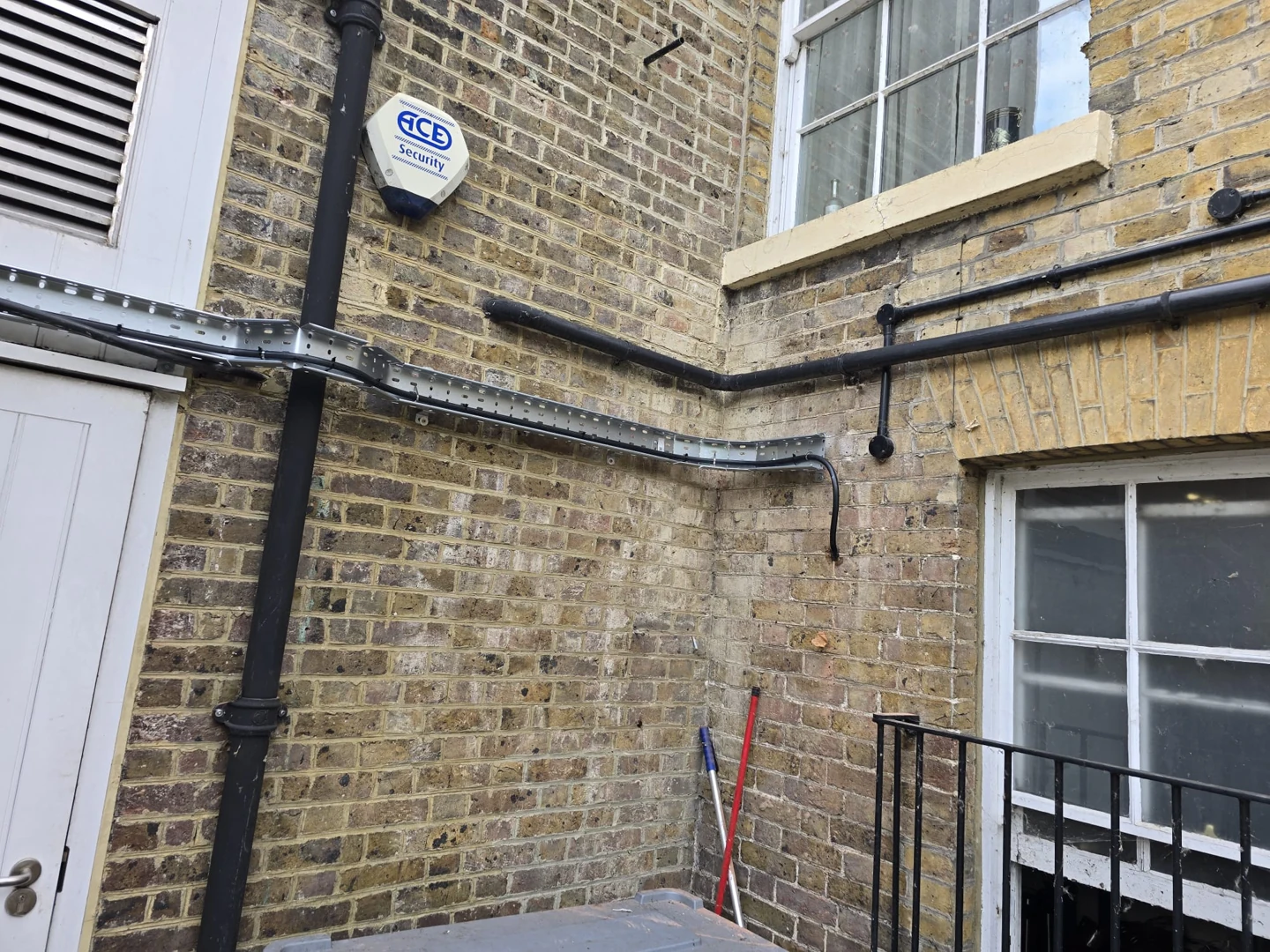External metal cable tray around a brick wall corner
